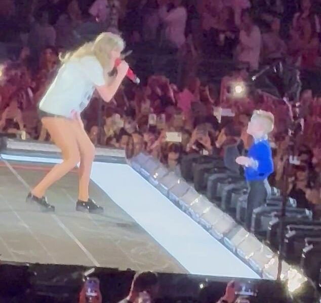 Adorable moment a young Swiftie has the ‘absolute time of his life’ as he is given Taylor Swift’s fedora while she sings to him